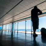 silhouette-of-passengers-waiting-on-open-terrace-in-airport