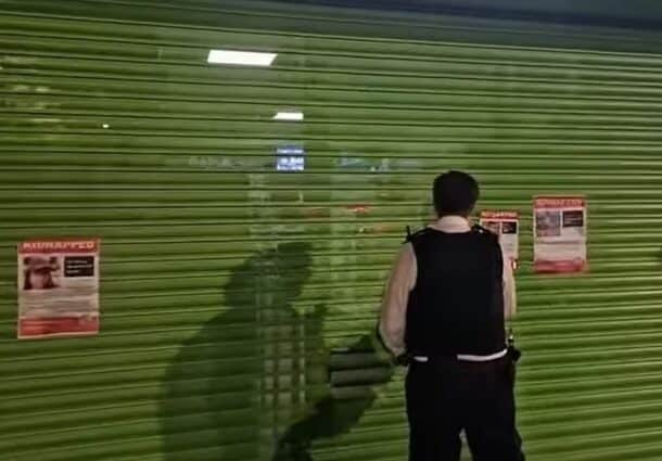 Moment Met Police officers pull down Jewish hostage posters from shop front