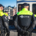 dutch-police-squad-formation-and-horseback-riding-mounted-police-back-view-with-police-logo-emblem-on-uniform-maintain-public-order-after-football-game-and-rally-in-the-streets-of-amsterdam-center