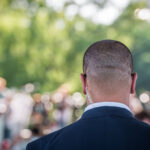 security-guard-listening-to-his-earpiece-on-event-back-of-jacket-showing-secret-service-guard-private-bodyguard-man-with-earpiece-in-crowd-black-suit-and-bald-head